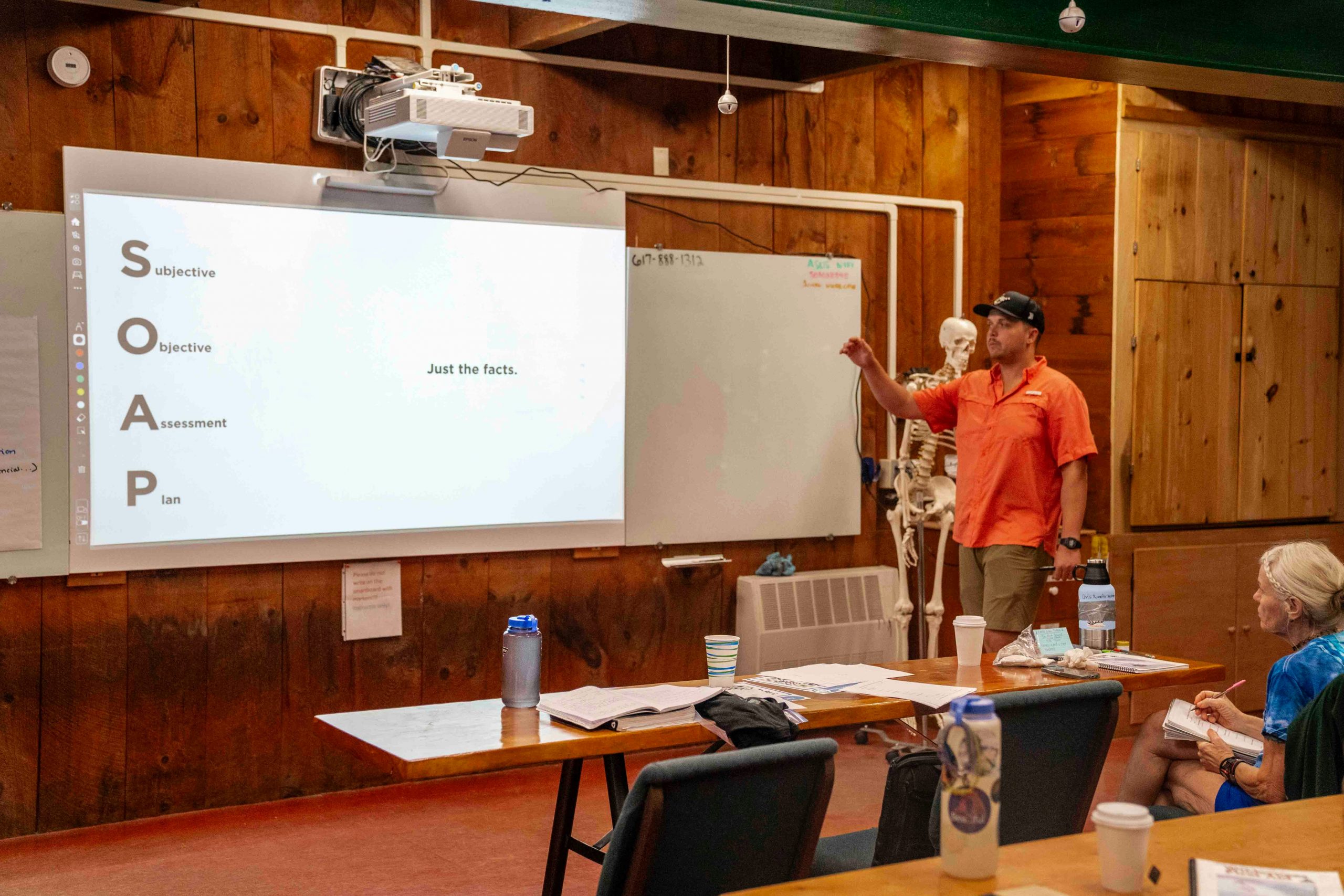 A professional trainer pointing at a screen showing ERP functionalities to a group of attentive employees in a workshop setting.