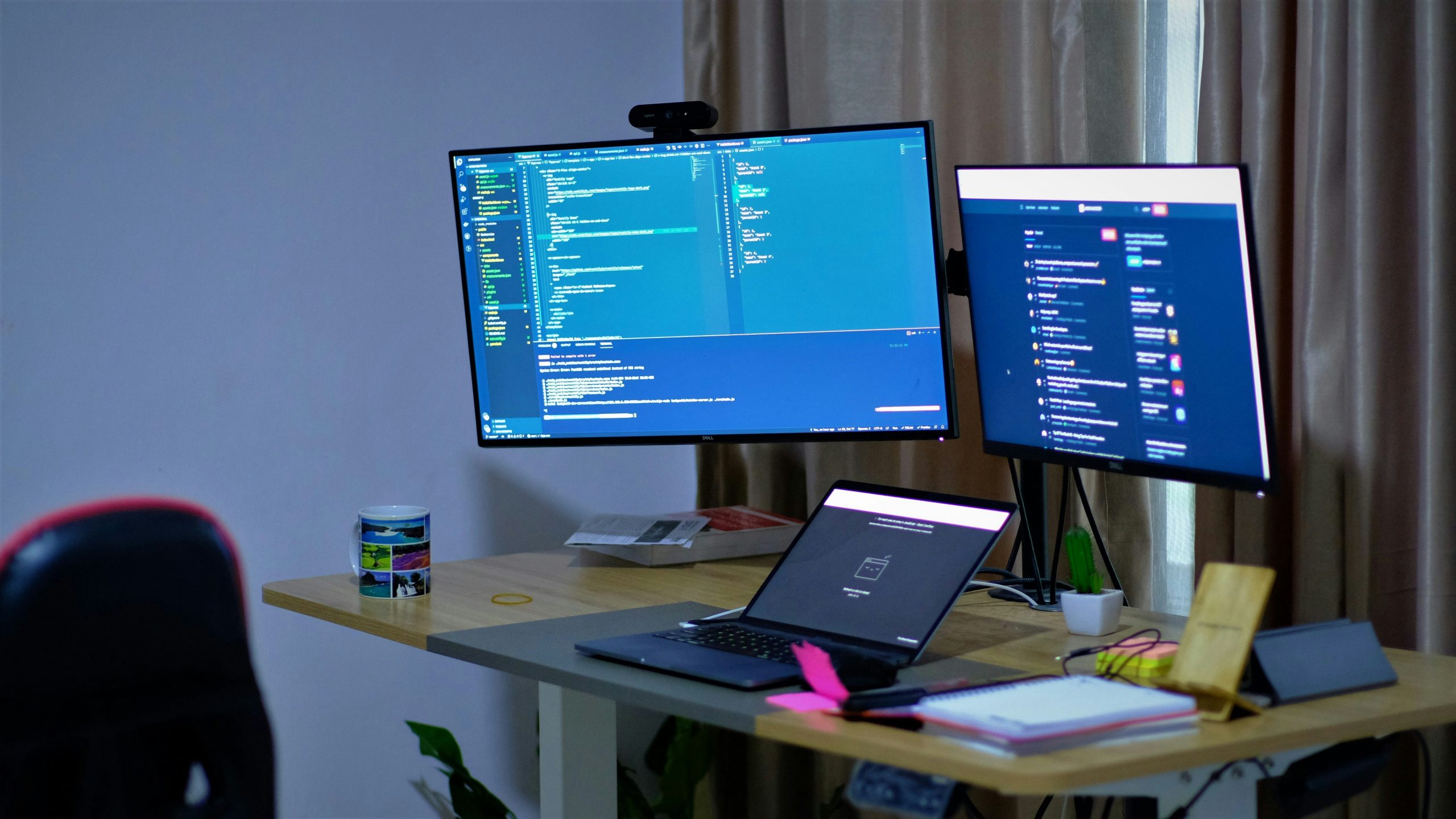 Modern office workspace with developer coding on dual monitors