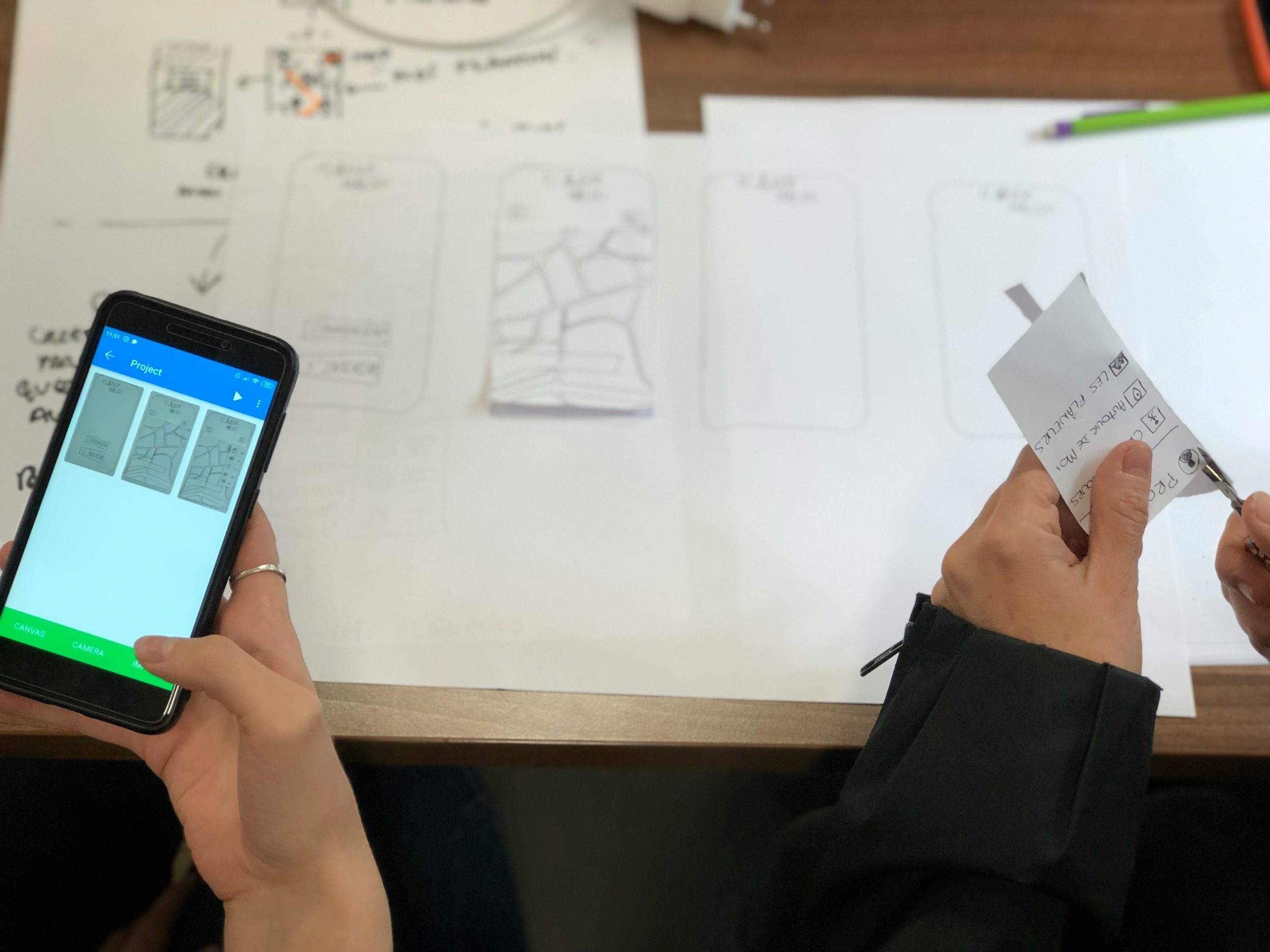 A professional team working around a table analyzing blueprints and digital mockups on a screen