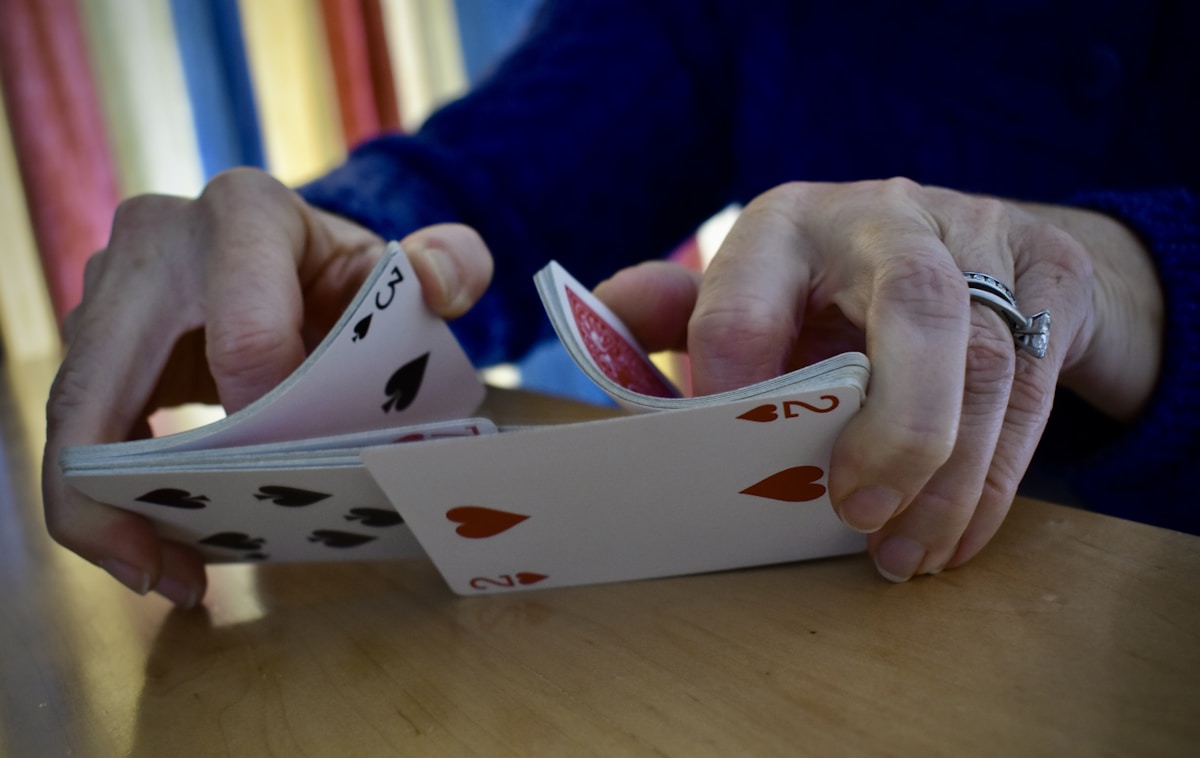Mains tenant des cartes de jeu de poker sur une table.