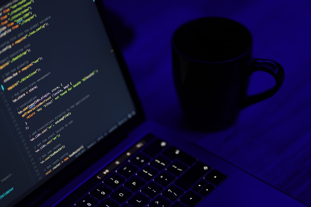 Code d'ordinateur, tasse de café, clavier sombre, éclairage bleu.