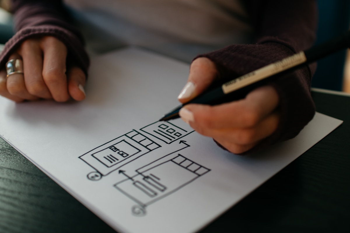 Mains dessinant un plan architectural sur papier.