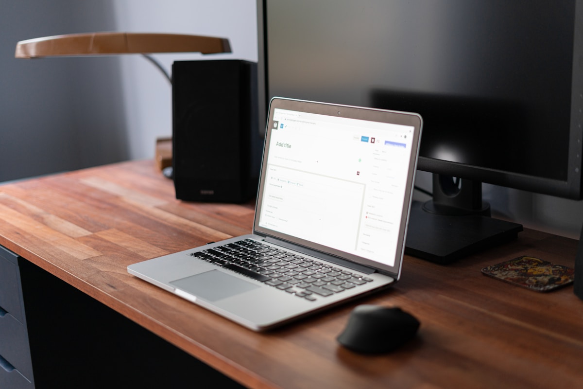 Bureau de travail avec ordinateur portable, haut-parleur et souris.