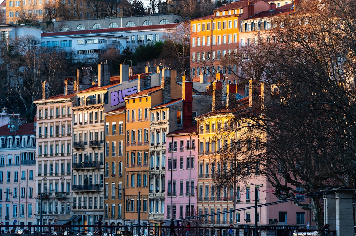 Quartier coloré de Lyon avec bâtiments historiques et arbres en automne.
