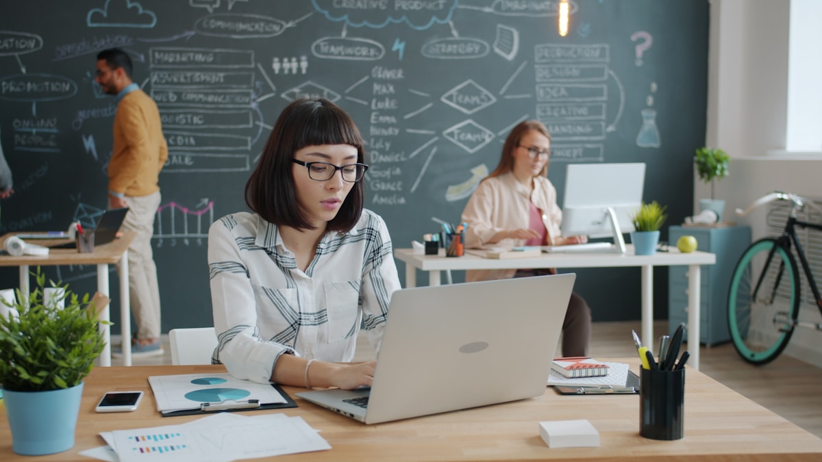 Jeune femme concentrée travaillant sur un ordinateur portable dans un bureau créatif.