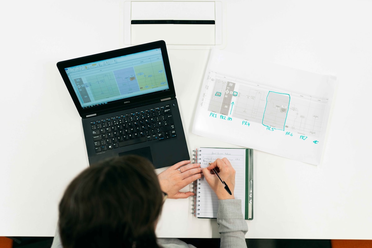 Ordinateur portable, cahier, plan, écriture, travail de bureau.