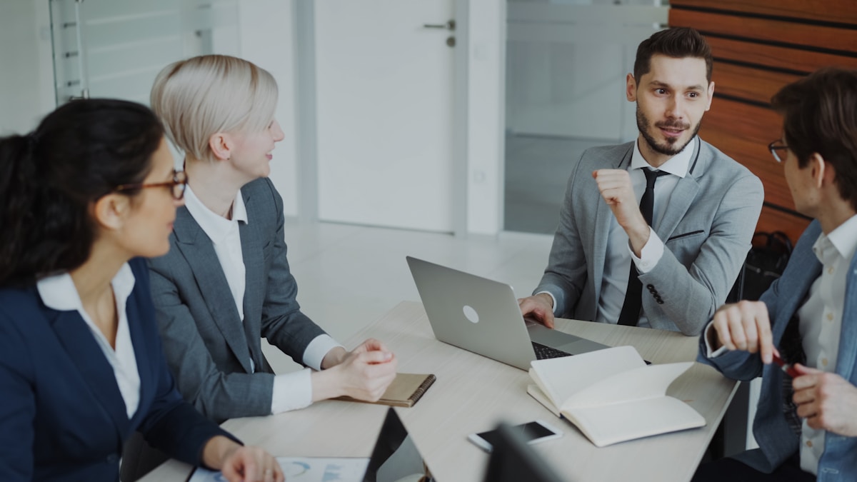 Réunion d'affaires avec des professionnels discutant autour d'un ordinateur portable.