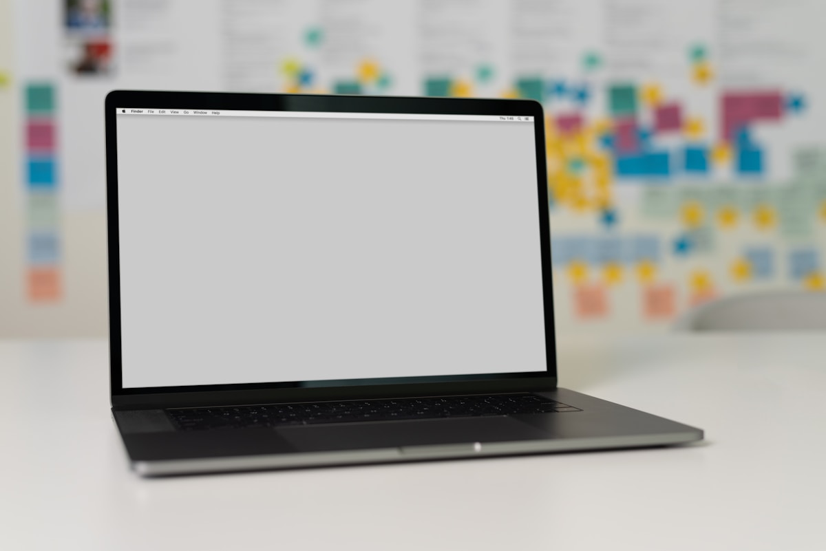 Ordinateur portable noir sur un bureau avec des notes colorées en arrière-plan.