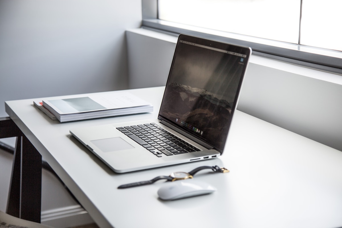 Bureau de travail avec ordinateur portable, souris et documents.