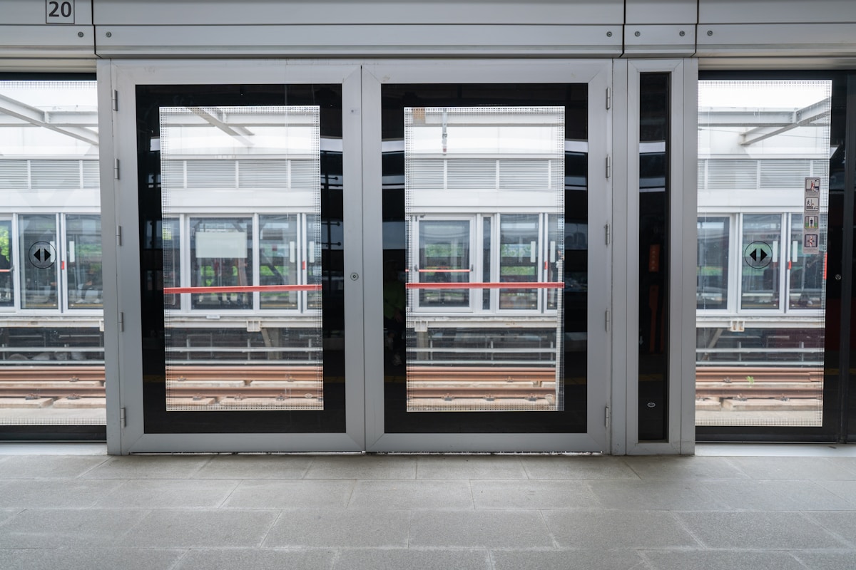 Portes vitrées d'un bâtiment moderne avec reflets extérieurs.