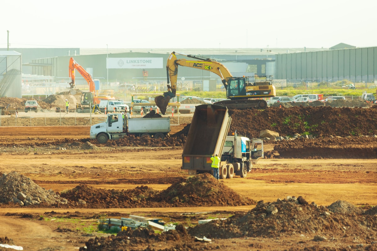 Chantier de construction avec excavateurs, camions et travaux de terrassement.