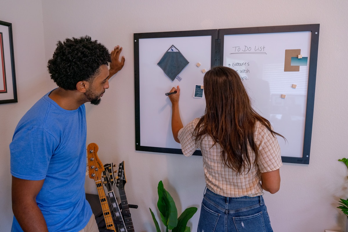 Deux personnes travaillant ensemble sur un tableau blanc dans un bureau.