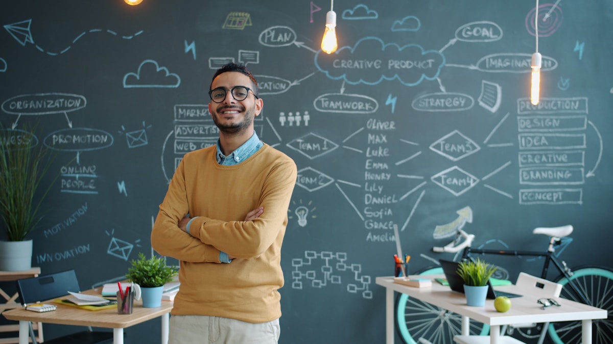 Homme souriant dans un bureau créatif avec un tableau blanc.