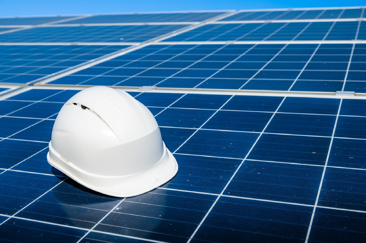 Casque de sécurité blanc sur des panneaux solaires bleus.