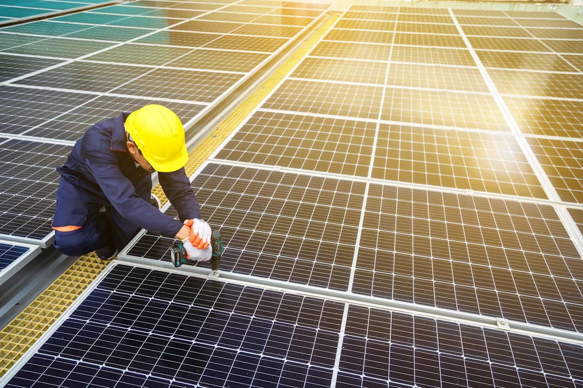 Ouvrier installant des panneaux solaires sur un champ photovoltaïque.