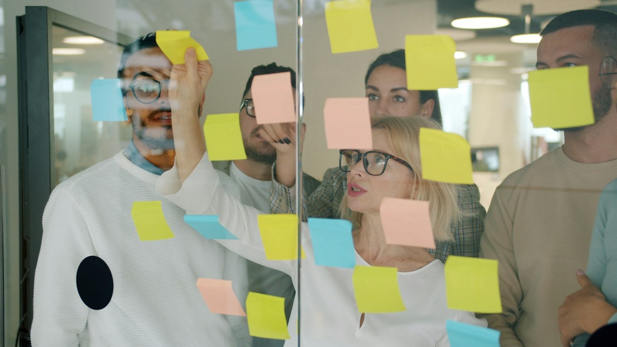 Équipe collaborative plaçant des post-it colorés sur une vitre.