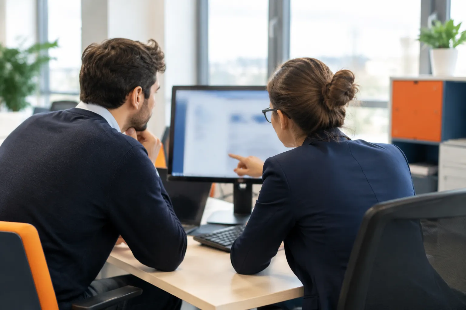 Collègues discutant devant un écran d’ordinateur au bureau.